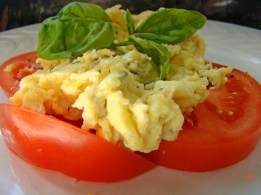 ovos mexidos sobre tomate fresco fatiado e manjericão