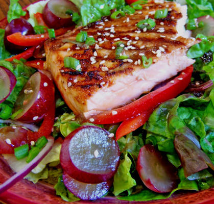 salmão grelhado com uvas em uma cama de verdes